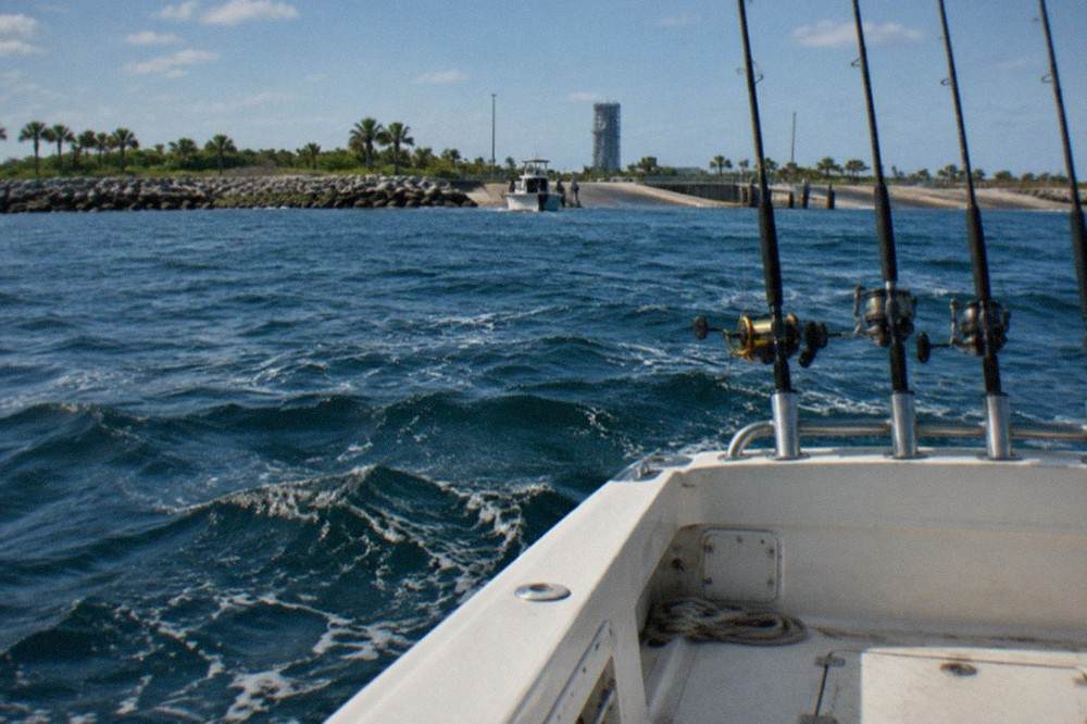 An offshore charter boat anchored over deep blue Atlantic water with rods in holders