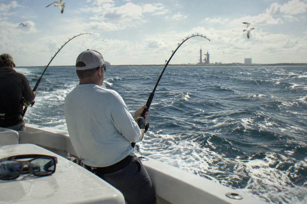 Rods bent over the side of a charter boat with open ocean horizon beyond