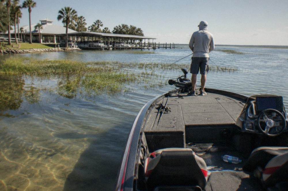 Bass boat drifting near grass beds on a wide Florida lake