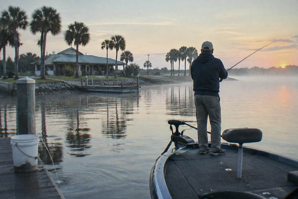 Angler casting a rod from the bow of a small boat at first light