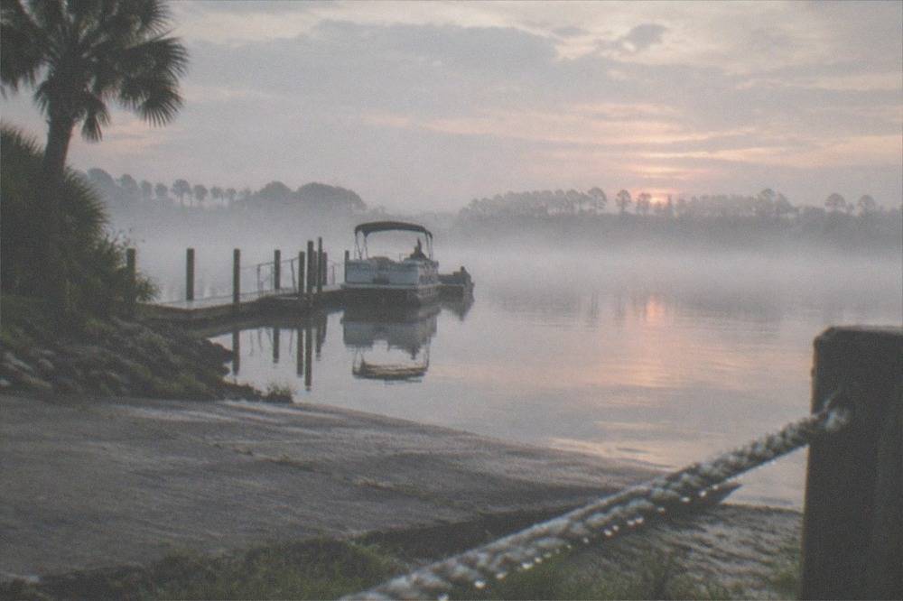 Early morning mist over a calm lake with distant treeline