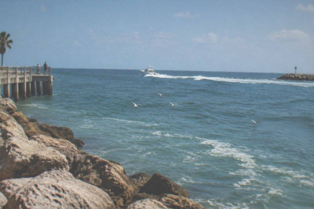 An offshore boat wake cutting across open Atlantic water under a bright sky