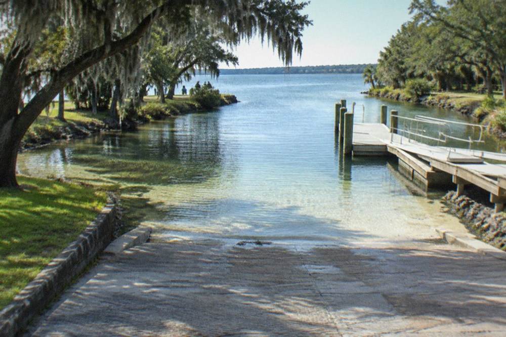 Clear spring-fed lake with visible grass beds and a boat channel between tree-lined shores