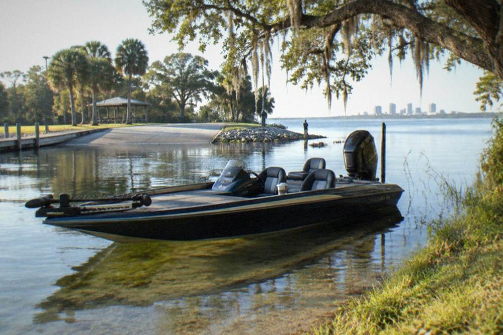 Bass boat anchored near a grassy shoreline on a calm morning