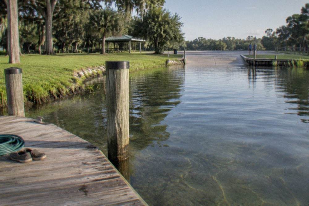 Clear lake water with grassy shoreline and a boat dock under morning light