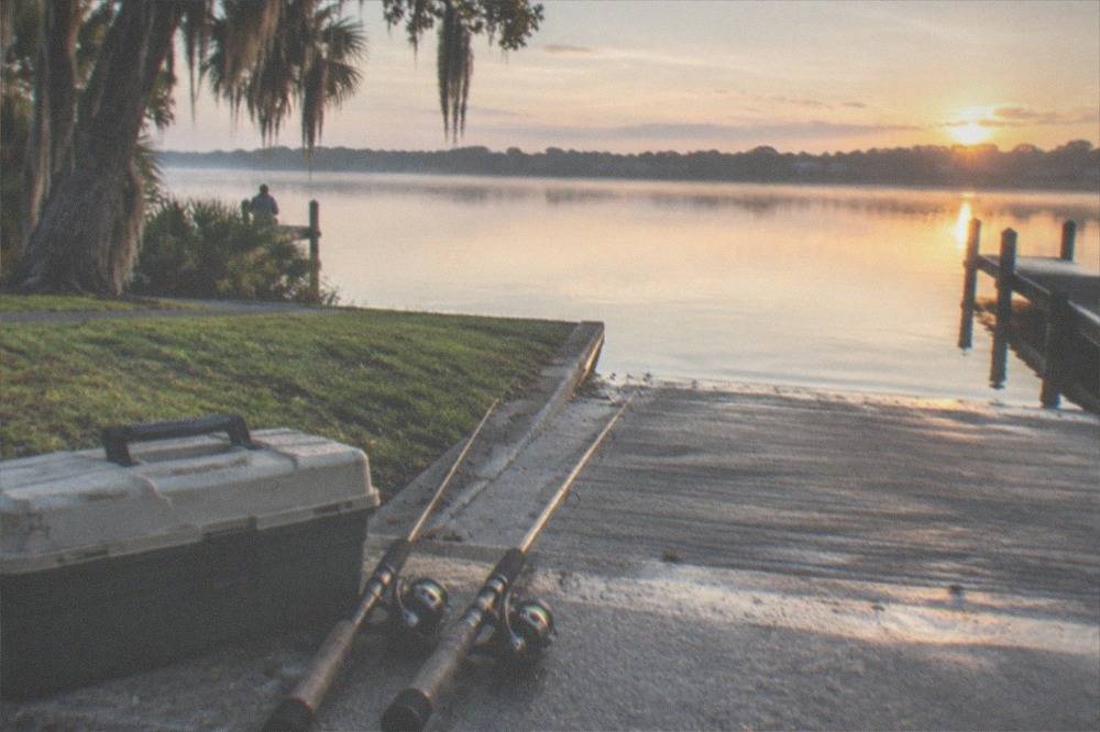 A tackle box and fishing rods staged on a dock before a morning launch