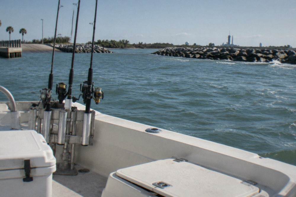 Fishing rods held upright in a rod holder on a boat deck with open water behind