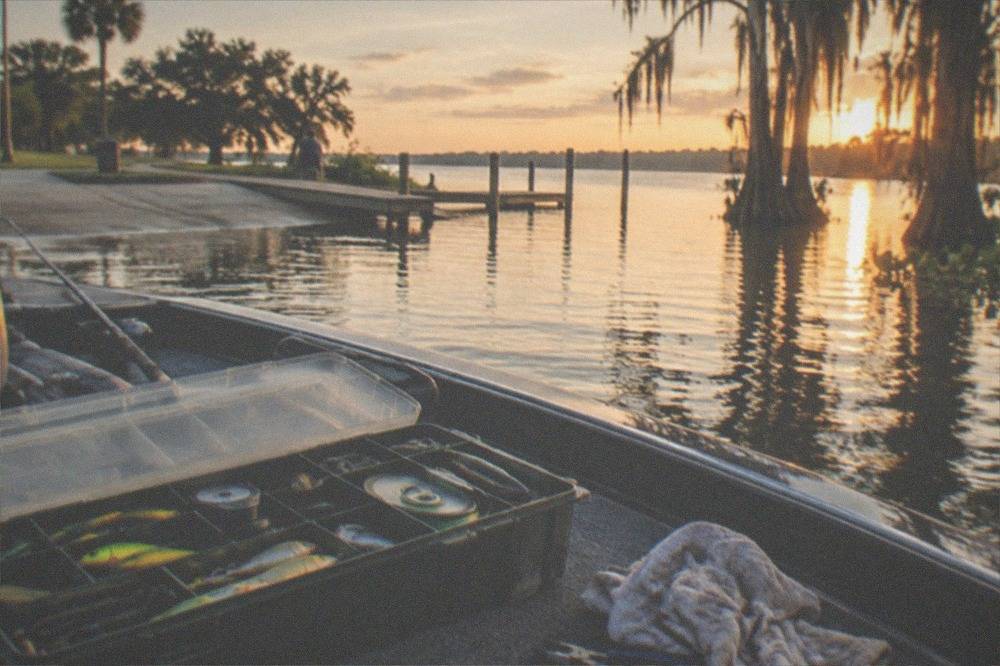 A tackle box open on a boat seat with lures and spools of line inside