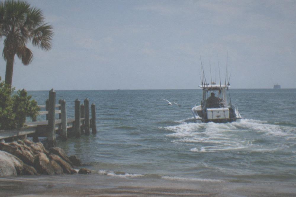 An offshore fishing boat cruising on open ocean water under a wide sky