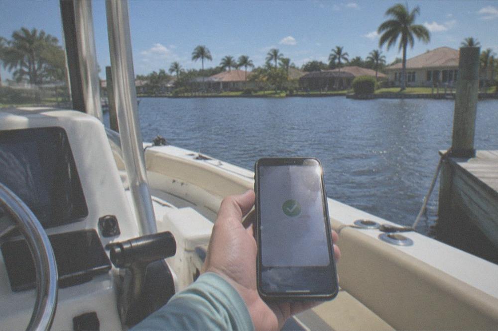 A smartphone displaying a confirmation screen held above a boat console