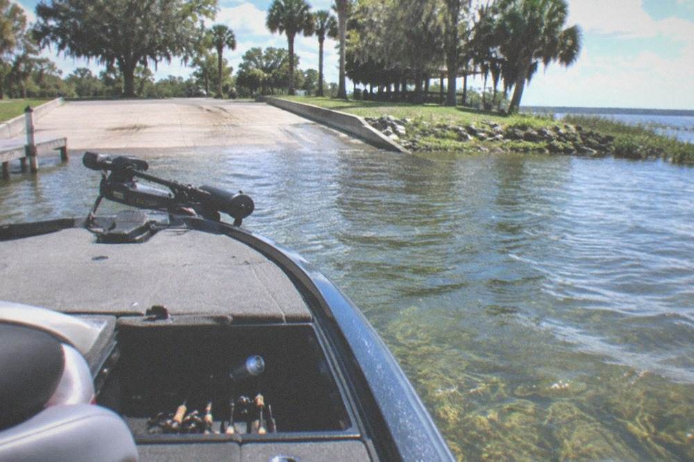 Bass boat anchored near a bed of lake grass at midday