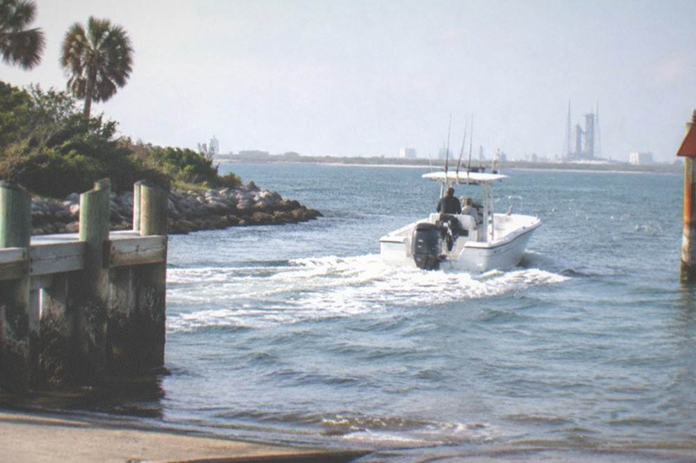 Center console charter boat running out toward open Atlantic water past a channel marker