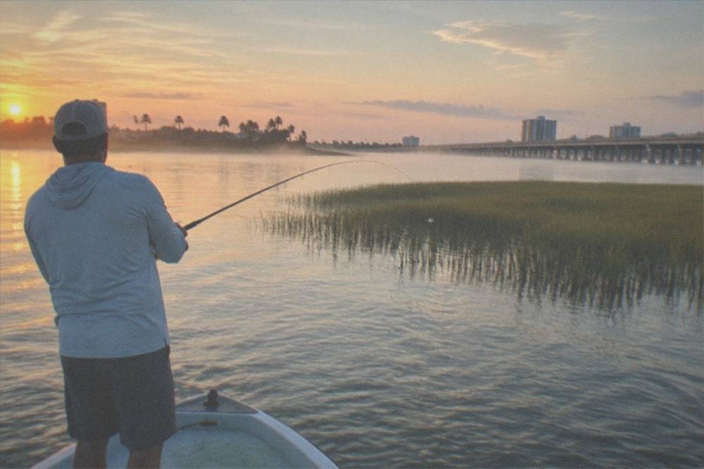 Angler casting toward a grass flat on a calm lagoon morning