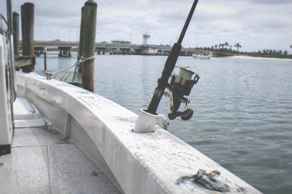 Fishing rod resting in a holder on a skiff deck with calm water beyond