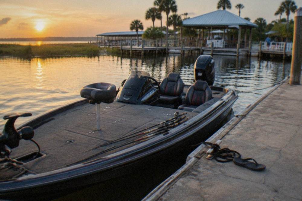 A private bass boat tied at a marina dock with rods racked along the side