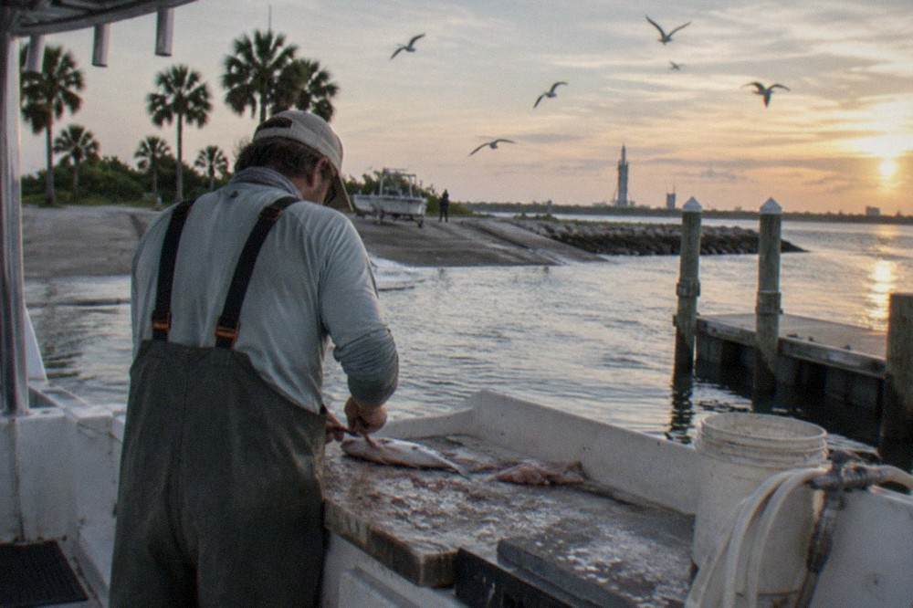 Charter captain cleaning fish at a cutting board on the boat deck