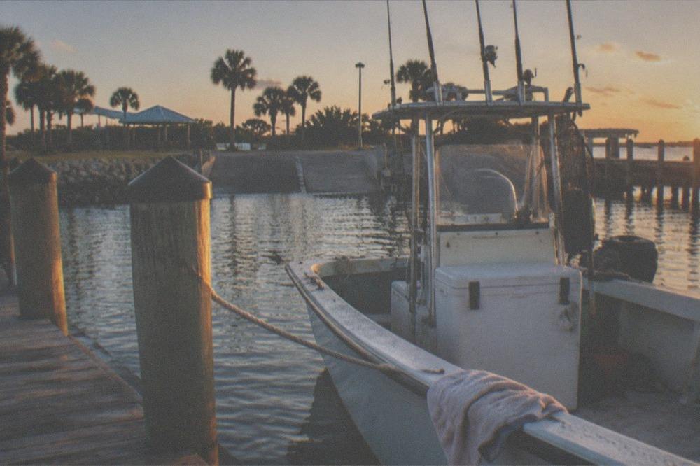 Marina dock at golden hour with a fishing boat tied up and gear stowed