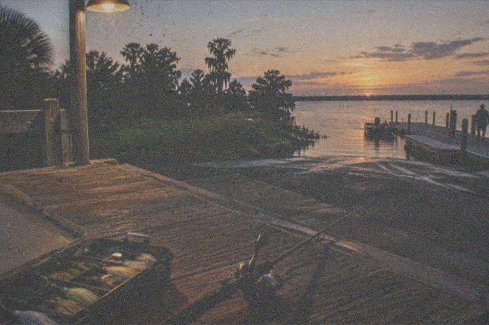 tackle box with lures arranged beside a fishing rod on a dock