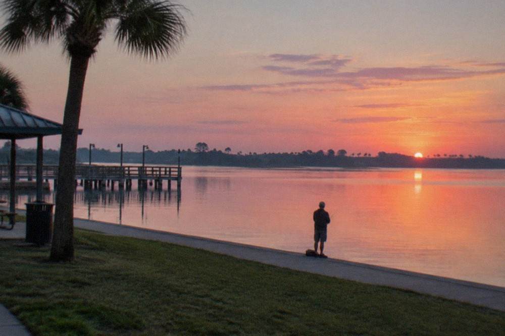 Sunrise over a large Florida bass lake with glassy water and distant treeline
